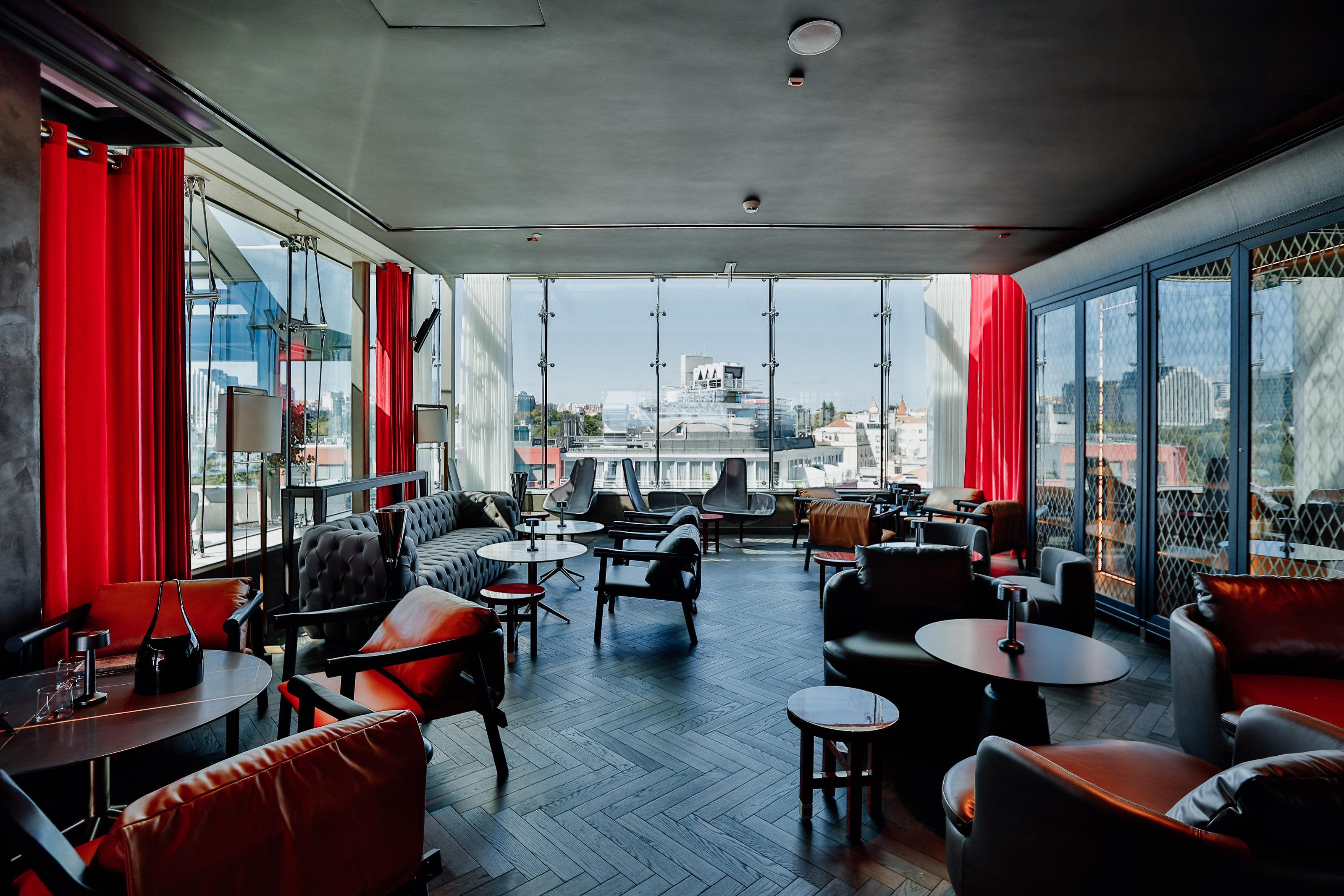 ליסבון Epic Sana Marques Hotel מראה חיצוני תמונה The photo shows a modern lounge or café interior with large windows allowing natural light to fill the space. There are several comfortable seating arrangements, including leather chairs and small round tables. The room features decorative elements l