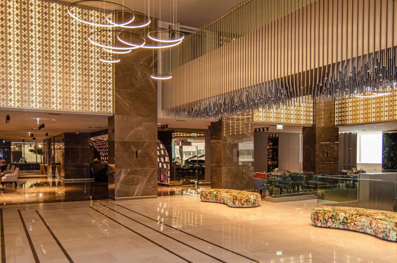 ליסבון Epic Sana Marques Hotel מראה חיצוני תמונה The photo depicts a modern and elegantly designed lobby or reception area of a hotel. The space features high ceilings with stylish light fixtures hanging from above, casting a warm glow. The walls are adorned with decorative elements, possibly with 