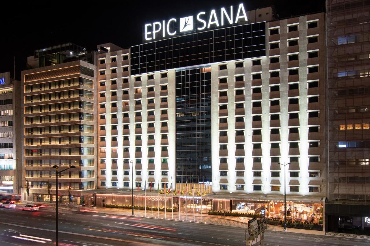 ליסבון Epic Sana Marques Hotel מראה חיצוני תמונה The photo shows the exterior of a hotel called "Epic Sana" illuminated at night. The building features a modern architectural design with large glass windows and bright lights that emphasize its facade. The hotel is situated next to a busy street, an