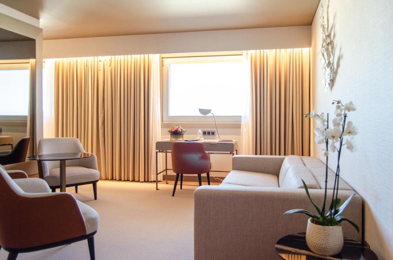 ליסבון Epic Sana Marques Hotel חדר תמונה The photo shows a modern and elegantly designed room that appears to serve as a living area or office space. The room features soft, neutral colors, with a warm, inviting atmosphere. 

There are large, light-colored curtains that hang over a window, 