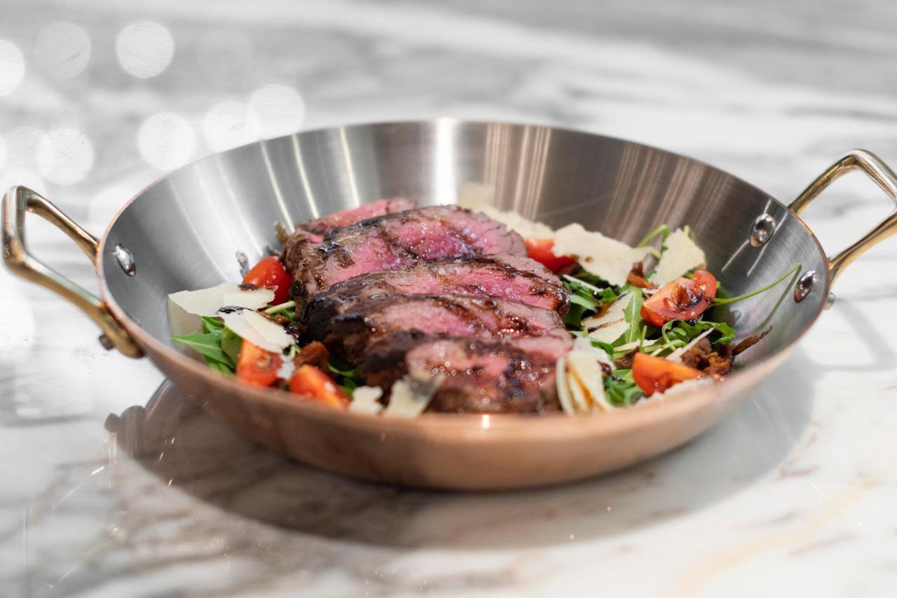 ליסבון Epic Sana Marques Hotel מראה חיצוני תמונה The photo showcases a beautifully plated dish featuring sliced steak arranged on a bed of vibrant salad greens. The steak appears to be grilled, showcasing a pink, juicy interior, and it is garnished with thin slices of parmesan cheese and diced toma