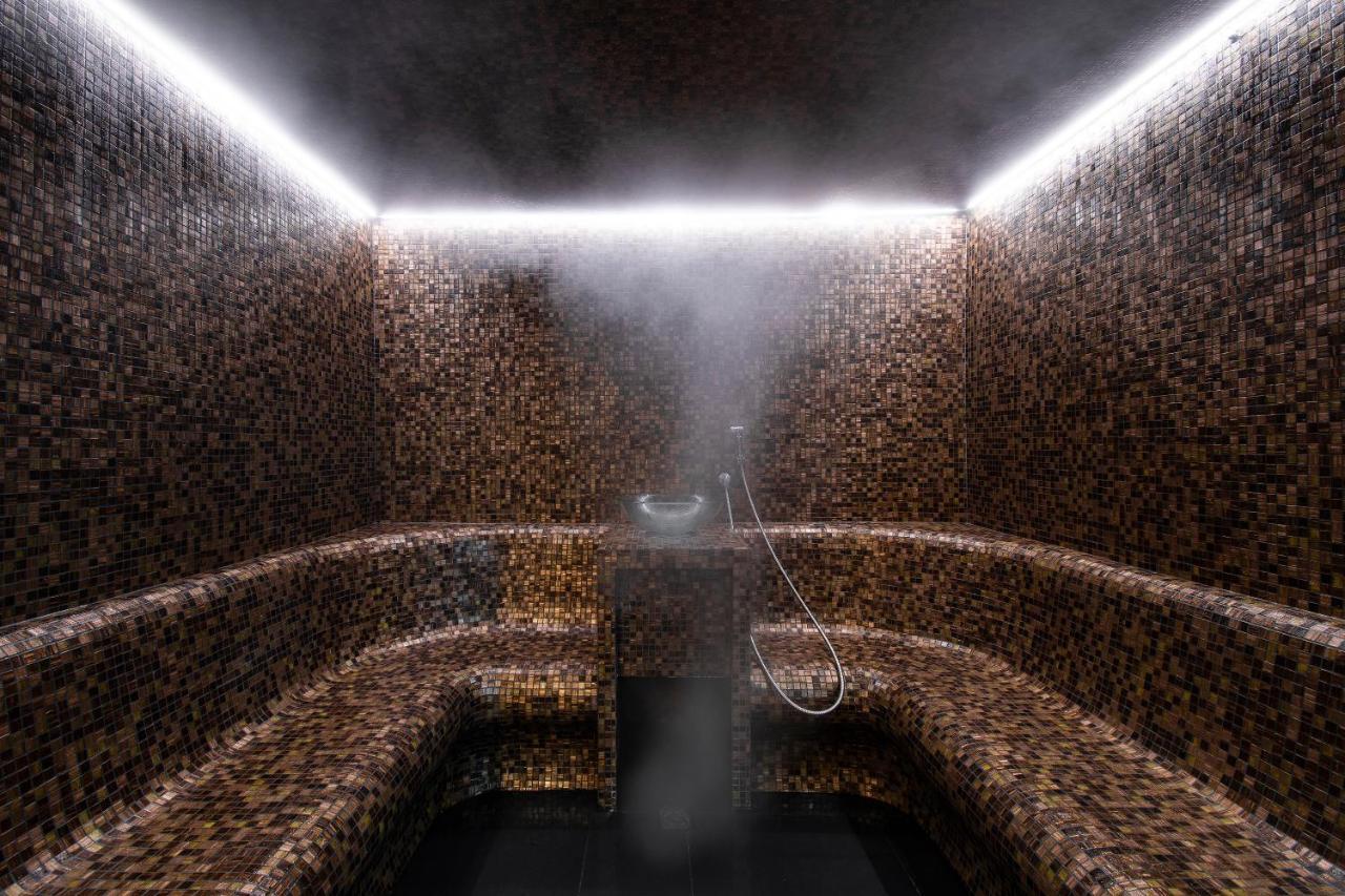 ליסבון Epic Sana Marques Hotel מראה חיצוני תמונה The photo shows a steam room or sauna interior. The space is designed with tiled walls and benches that create a cozy and luxurious atmosphere. Soft, ambient lighting is provided by LED strips along the ceiling. Steam is visible in the air, indicatin