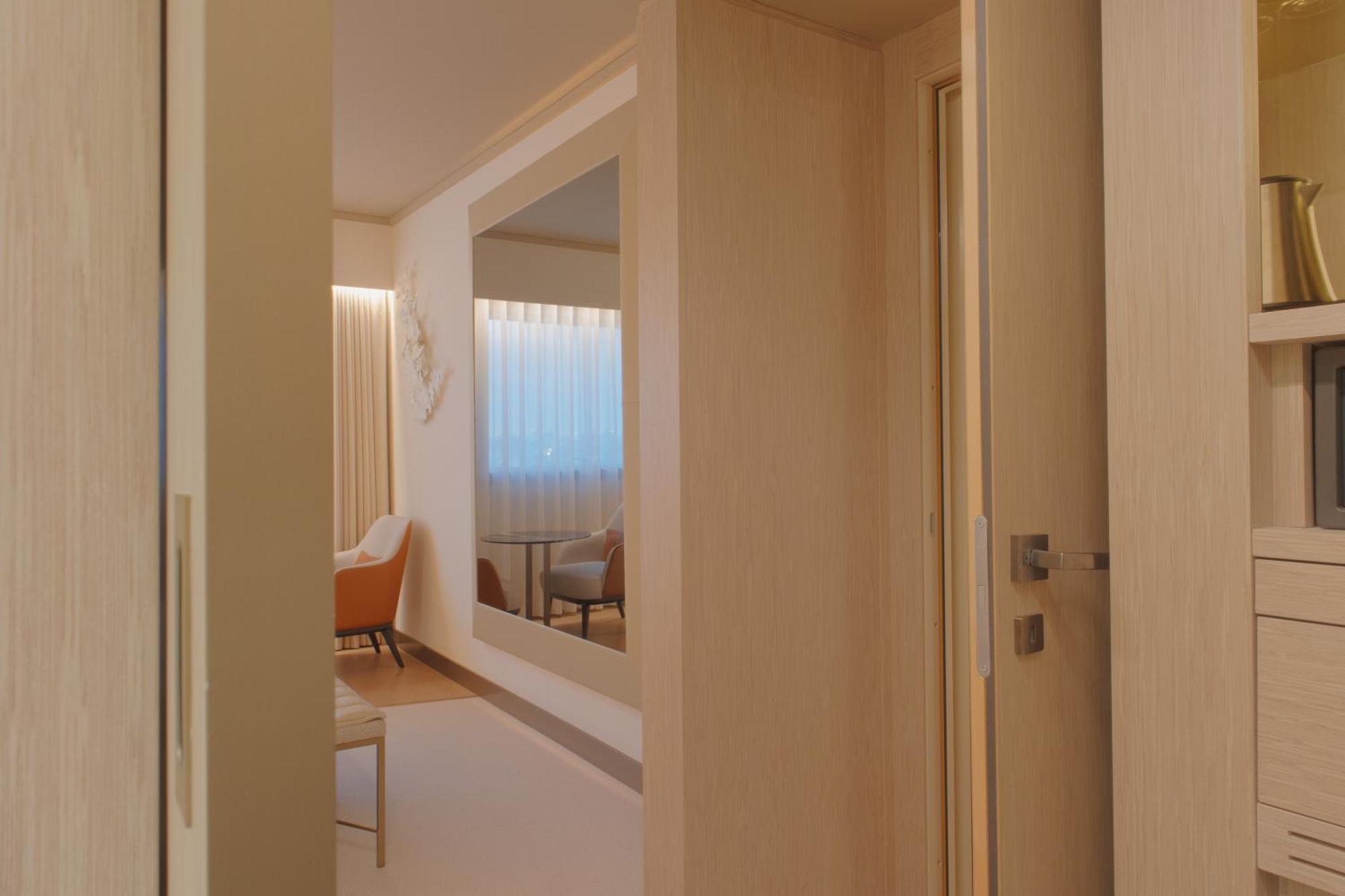 ליסבון Epic Sana Marques Hotel מראה חיצוני תמונה The photo depicts a modern interior space, likely a room or hallway. There is a doorway on the left, leading into another area. On the right, a large mirror is mounted on the wall, reflecting light and creating a sense of openness. In the background,